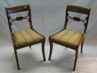 A set of 4 Regency bar back dining chairs with shaped mid rails and upholstered drop in seats, on sabre supports