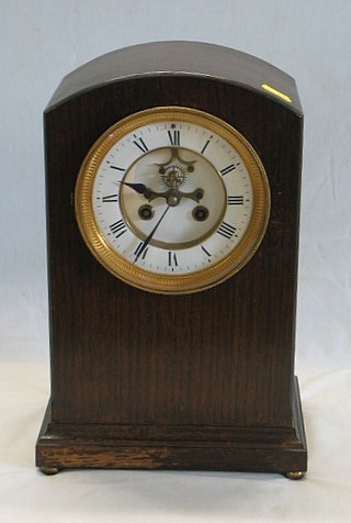A 19th Century French 8 day striking  mantel clock with porcelain dial and Roman numerals, having visible escapement, contained in an oak arched case