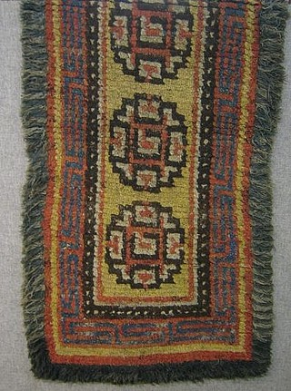 A Tibetan green ground wool rug with 3 octagons to the centre 66" x 33"