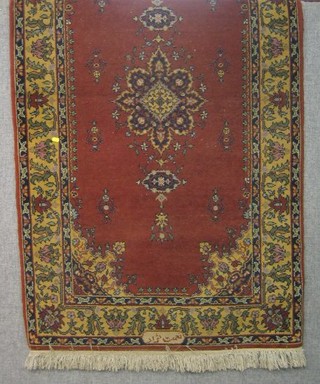 A red ground Persian carpet with central medallion within floral border, signed, 69" x 40"
