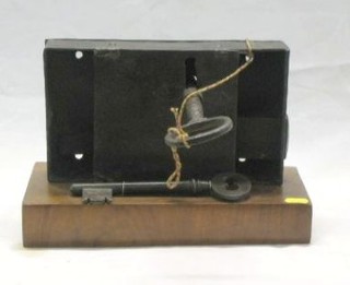 An early iron lock complete with 2 keys 11", raised on a walnutwood base