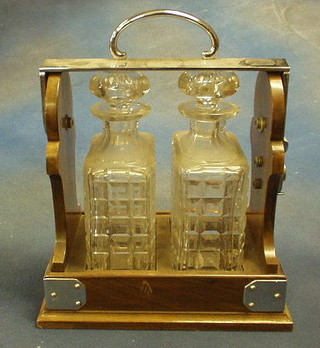 An Edwardian 2 bottle tantalus with 2 rectangular cut glass spirit decanters, contained in a walnutwood case with silver plated mounts and Betjemann's Patent