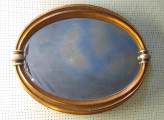 An oval bevelled plate wall mirror contained in a decorative gilt frame 39"