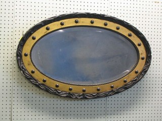 A 19th Century oval bevelled plate wall mirror contained in a black and gilt ball studded frame 29"