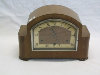 An Art Deco chiming mantel clock with arched dial contained in a walnutwood case