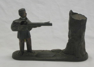 A 19th Century iron money box in the form of a standing soldier shooting at a tree stump 10"