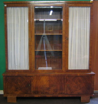 An Art Deco Continental Kingwood display cabinet on cabinet, the upper section fitted adjustable shelves enclosed by bevelled plate panelled doors, the base fitted 3 cupboards enclosed by double doors, raised on block supports, 65"