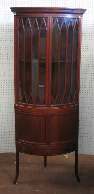 A 19th Century mahogany bow front corner cabinet with moulded and dentil cornice, the shelved interior enclosed by astragal glazed panelled doors, the base fitted a double cupboard enclosed by panelled doors and 1 long drawer, raised on splayed supports 28"