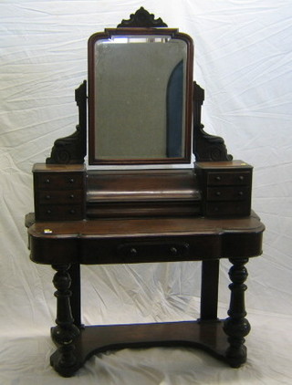 A Victorian walnutwood Duchess dressing table with arched bevelled plate mirror to the back, fitted a shaped recess to the centre enclosed by a scrolled lid and having 6 glove drawers, the base fitted 1 long drawer, raised on bulbous turned supports 44"