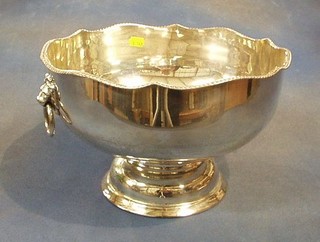A large silver plated punch bowl with wavy border and lion mask drop handles, raised on a circular foot 12"