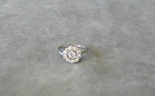 A lady's white gold dress ring set a circular cut diamond surrounded by 10 diamonds and 6 diamonds to the shoulders (approx 0.76ct)