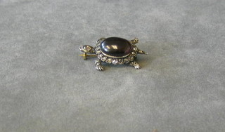 A gold brooch in the form of a turtle, set a cabouchon cut garnet surrounded by diamonds