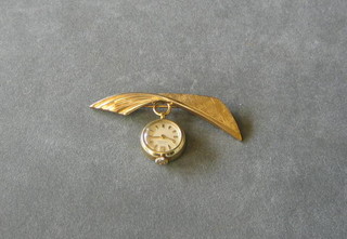 A gold watch hung on a gilt metal fob brooch