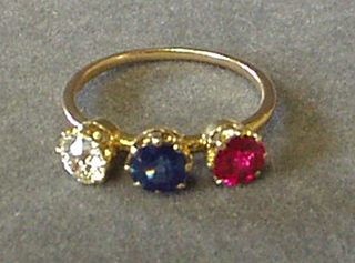 A lady's gold dress ring set a diamond, a red stone and a blue stone