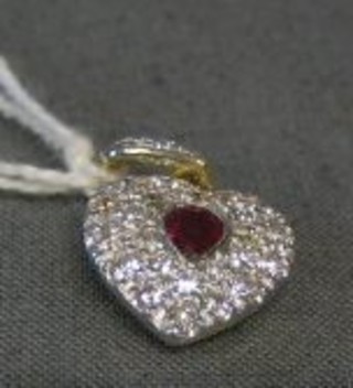 A lady's 18ct gold heart shaped pendant set a heart cut ruby surrounded by numerous diamonds