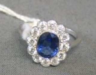 A lady's attractive 18ct white gold dress ring set an oval cut sapphire and surrounded by 12 diamonds (approx 0.85/1.43)
