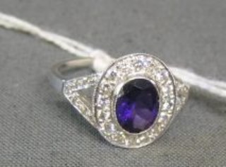 A lady's 18ct white gold dress ring set an oval cut amethyst surrounded by numerous diamonds and with diamonds to the shoulders