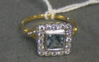 A lady's 18ct gold gold dress ring set a square cut aquamarine surrounded by 16 diamonds
