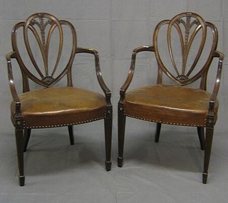A fine quality pair of 19th Century mahogany Hepplewhite style shield back open arm chairs, the seats upholstered hide, on square fluted reeded supports ending in spade feet