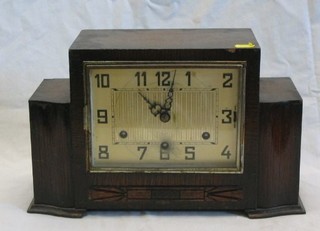 An Art Deco chiming mantel clock with square dial contained in an oak case