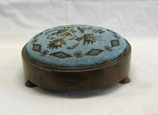 A circular Victorian mahogany footstool with bead work seat, raised on turned supports 11"