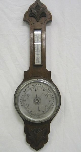 A Wheel aneroid barometer and thermometer with silvered dial contained in an oak case