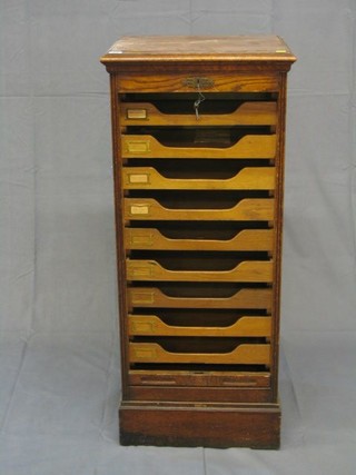 An Edwardian honey oak pedestal filing chest, the top with hinged reading slope enclosed by a tambour shutter 19"
