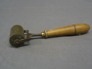 A 19th/20th Century iron and brass finger print ink roller with turned handle