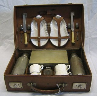 A Barrett & Sons 1920's 15 piece picnic set with 2 steel Thermos flasks, 2 circular steel storage jars, sandwich box with lid (hinge f), 4 cups and saucers, 2 knives and 4 silver plated Old English pattern teaspoons and a pair of sugar tongs, in original leather carrying case with plated mounts, the lid marked Barrett & Sons to the Royal Family 63 and 64 Piccadilly London,