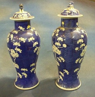 A pair of Oriental baluster shaped lidded vases decorated Prunus trees 13"