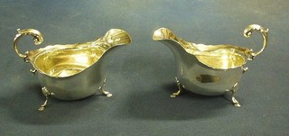 A pair of silver sauce boats with wavy borders and C scroll handles, raised on hoof feet Birmingham 1925 6 ozs