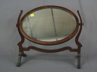 An oval bevelled plate dressing table mirror contained in a mahogany swing frame