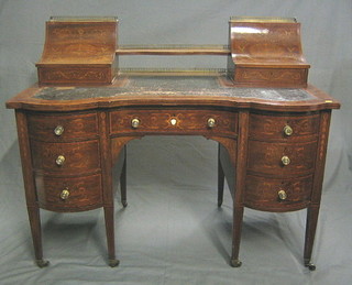 A handsome Maples & Co Edwardian inlaid mahogany Carlton House writing table, the raised back with pierced brass three-quarter gallery and 2 stationery boxes, the writing surface inset tooled leather above an arrangement of 8 drawers with brass handles, raised on square tapering supports ending in brass caps and castors 48"