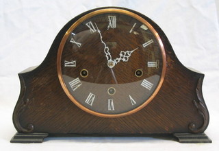 A 1930's 8 day chiming mantel clock with Roman numerals contained in an oak arched case
