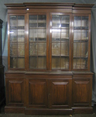 A Georgian style triple breakfront mahogany bookcase, the upper section with moulded and dentil cornice fitted adjustable shelves, the base fitted 3 cupboards enclosed by panelled doors, raised on platform base 64"