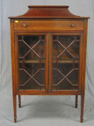 An Edwardian inlaid mahogany cabinet with raised back, fitted a drawer above a double cupboard fitted a shelf enclosed by astragal glazed panelled doors, raised on square tapering supports and spade feet
