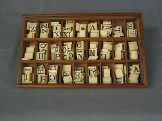 A mahogany box containing a collection of ivory "scrabble" letters