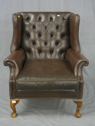 A Georgian style mahogany framed wing armchair upholstered in buttoned hide, on cabriole supports