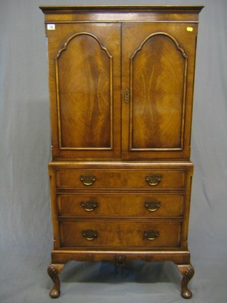 A 1930's Queen Anne style walnutwood cocktail cabinet with moulded cornice enclosed by panelled doors, the base fitted 3 long drawers, raised on cabriole supports 28"