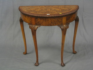 A 1930's figured walnutwood demi-lune table with gadrooned borders, raised on cabriole supports 33"