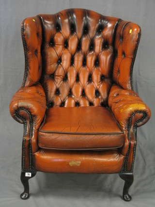A Georgian style mahogany framed wing armchair upholstered in buttoned brown leather