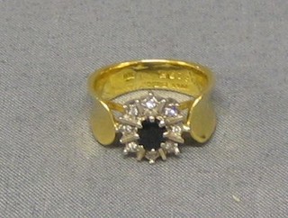 An 18ct gold dress ring set a sapphire, supported by numerous diamonds