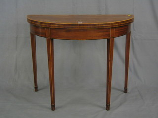 A Georgian mahogany demi-lune folding tea table with crossbanded top, raised on square tapering supports ending in spade feet 36"