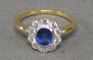 A lady's gold dress ring set an oval cut sapphire surrounded by 10 diamonds (approx 0.50ct)