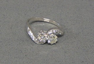A lady's 18ct white gold 2 stone diamond set cross-over engagement/dress ring, set 12 smaller diamonds (approx 0.93ct)