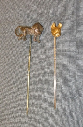 A gilt metal stick pin in the form of a walking lion and a gilt metal stick pin in the form of a "Boxer" dog head