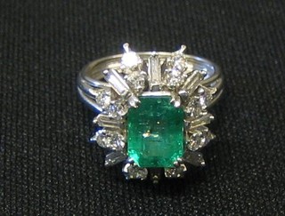 A lady's 18ct white gold dress ring set a rectangular cut emerald supported by 8 baguette cut diamonds and 16 other diamonds
