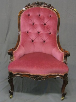 A Victorian carved rosewood show frame nursing chair, upholstered pink buttoned material, the seat of serpentine outline and raised on cabriole supports