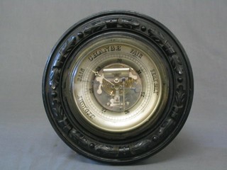 An Edwardian aneroid barometer contained in a carved ebony case