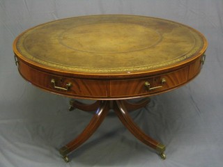 A handsome Georgian style mahogany drum table, set a tooled leather surface, fitted 4 frieze drawers, raised on gun barrel tripod column supports ending in brass caps and castors (purchased at Harrods) 47"